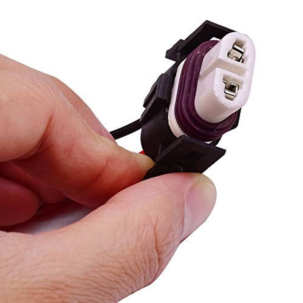 Ceramic headlight connector plug held by hand, showing two metal terminals