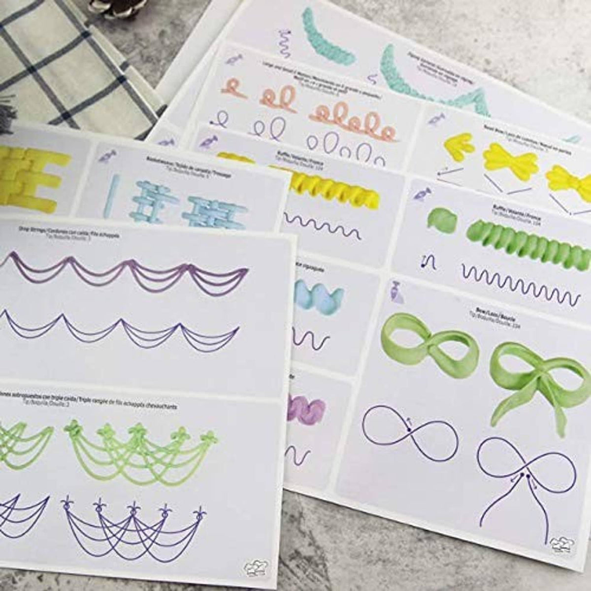 Assorted cake piping pattern sheets on boards, including bows, vines, and scallops