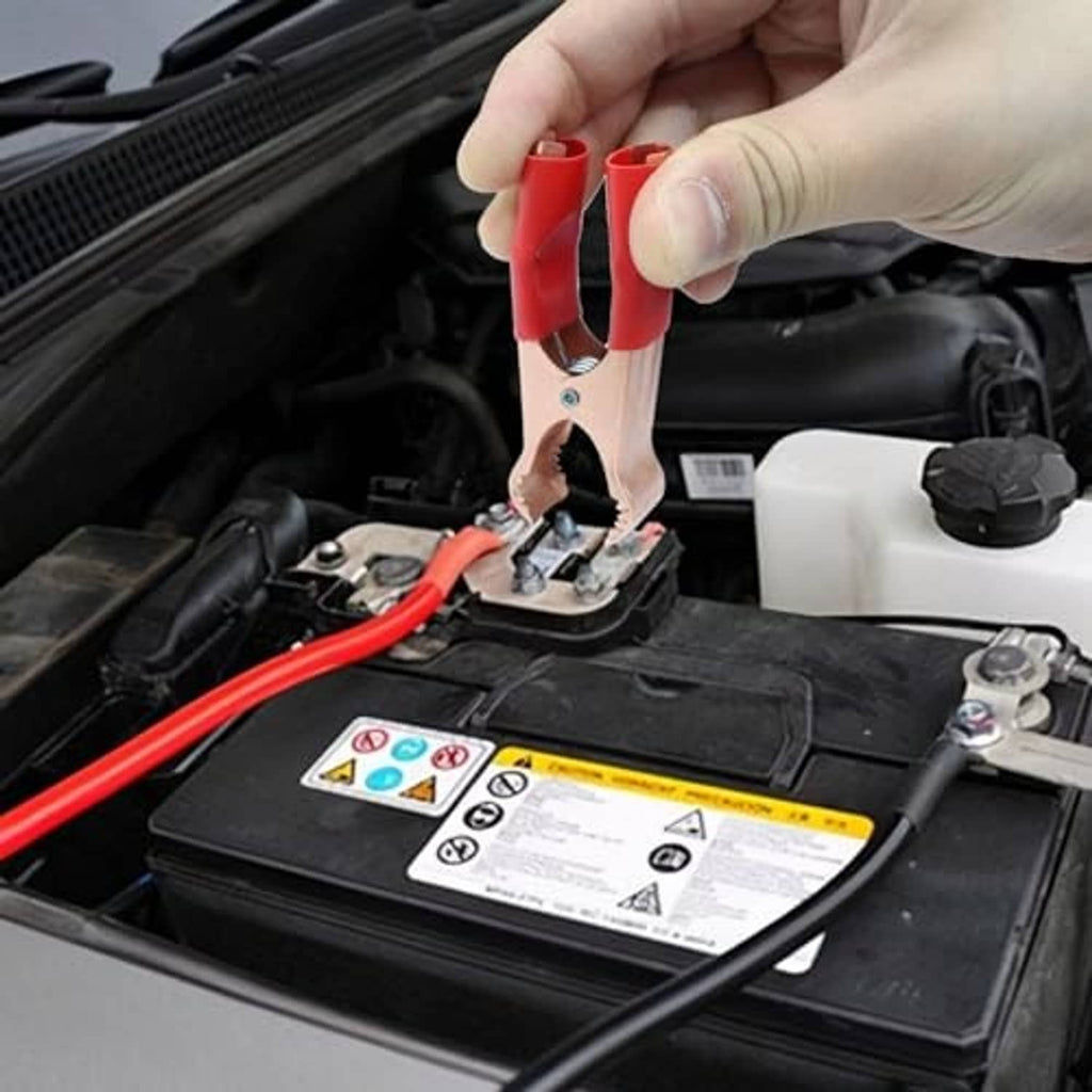 Insulated alligator clip attached to car battery terminal with red insulated jaw