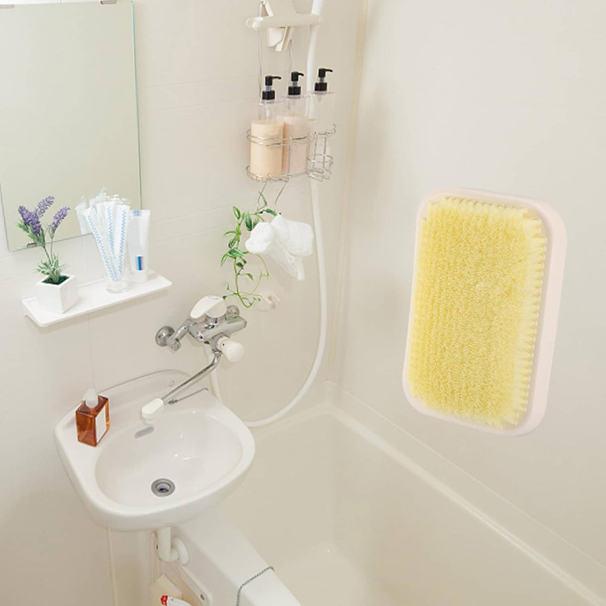 Wall-mounted back scrubber with yellow exfoliating pad attached beside shower tub