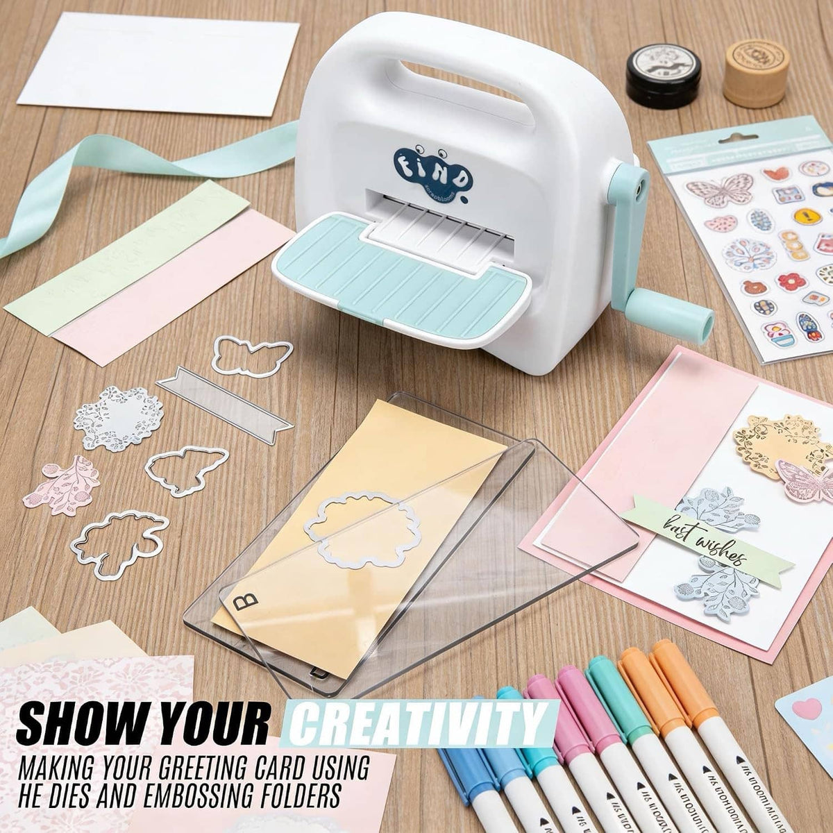 White and teal mini die cutting machine with cutting plate and paper crafts nearby