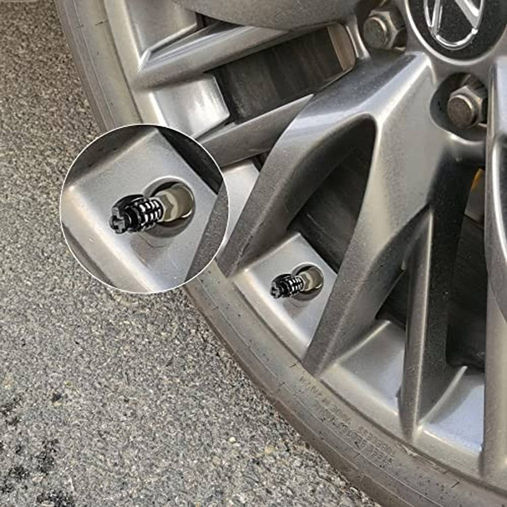Black tire valve stem caps installed on silver alloy wheel rim spokes
