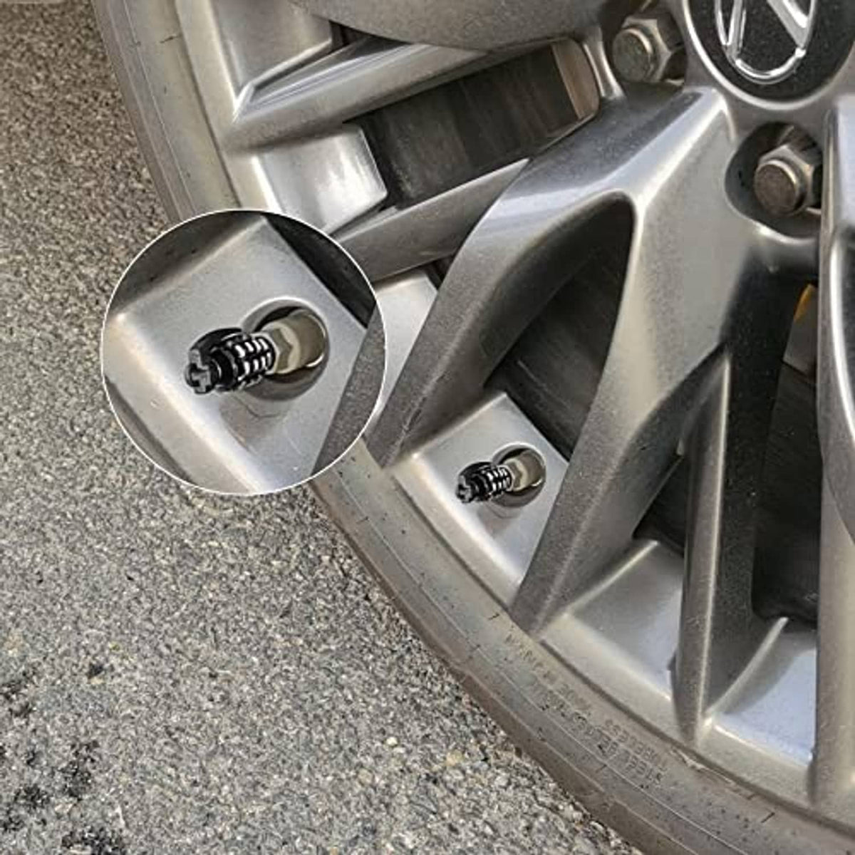 Black tire valve stem caps installed on silver alloy wheel rim spokes