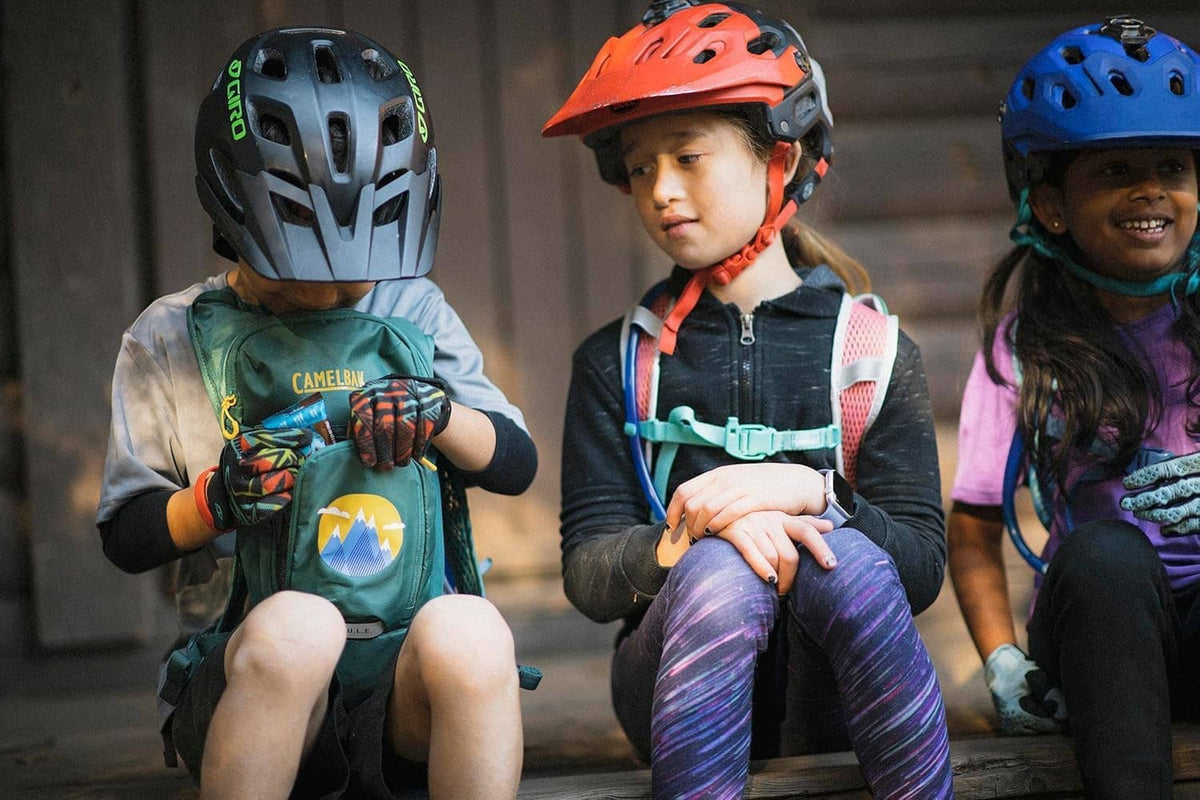 Kids hydration backpack worn by children, blue shark print with Camelbak logo and straps