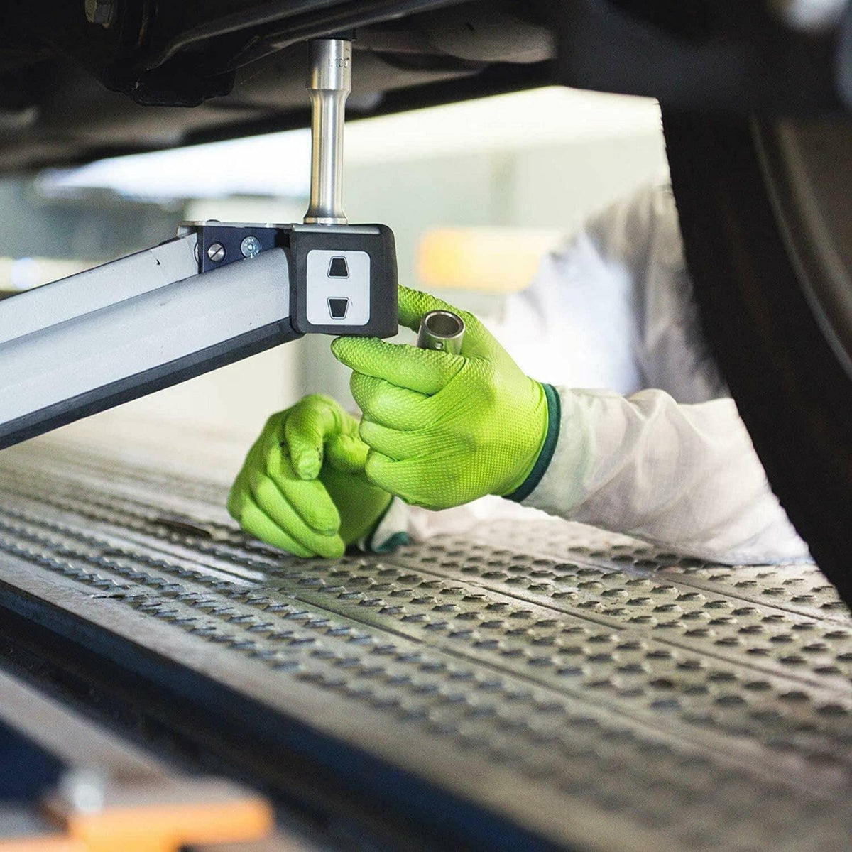 Green nitrile glove with textured grip pressing on vehicle panel