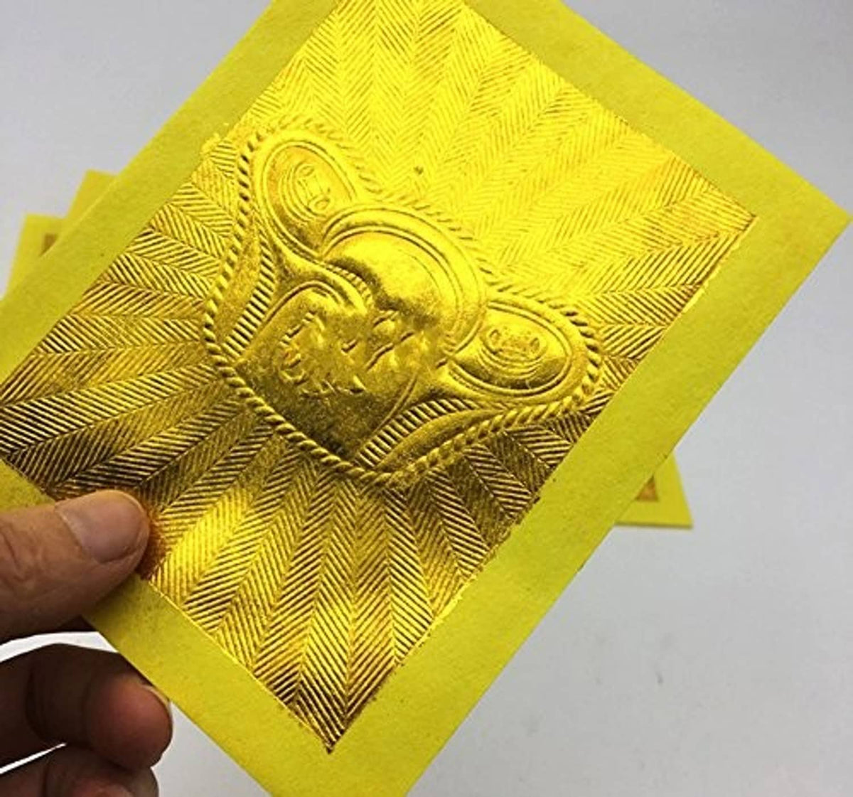 Zeestar joss paper close-up held in hand, rectangular gold foil embossed blessing emblem