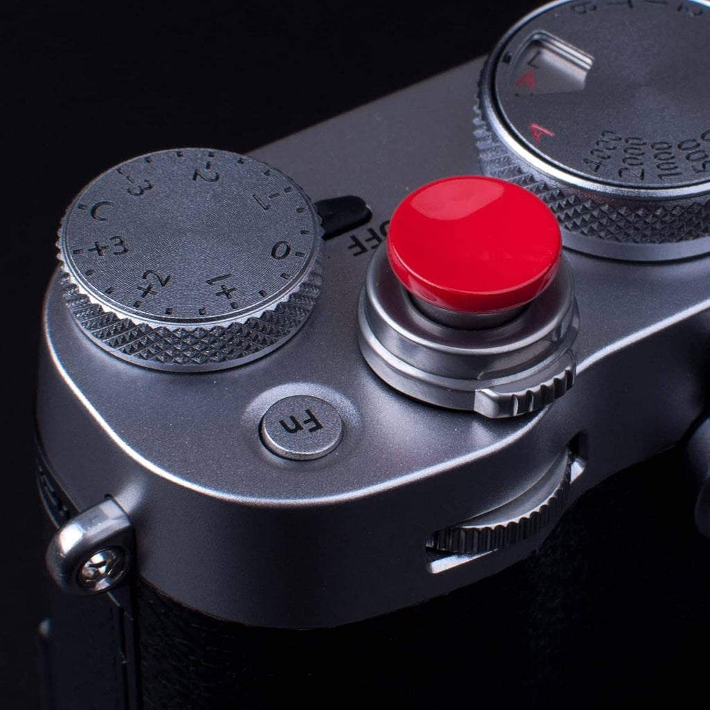 Red domed shutter release button on camera top next to dials and controls.
