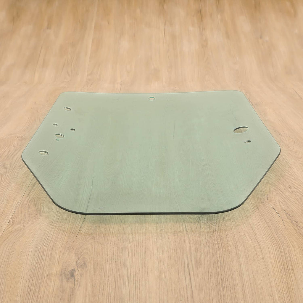 Green-tinted cab door glass panel with mounting holes; curved bottom edge.