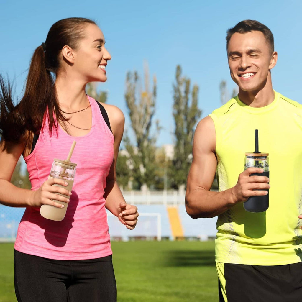 Black silicone-sleeved glass tumbler with straw held during outdoor activities