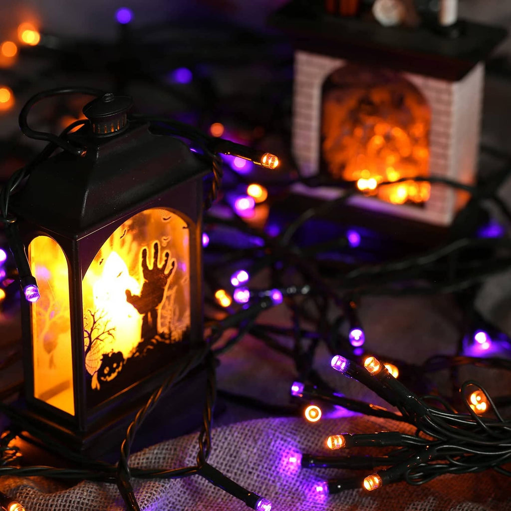 Solar lantern-style Halloween lights with orange glow and purple LED bulbs on black wire
