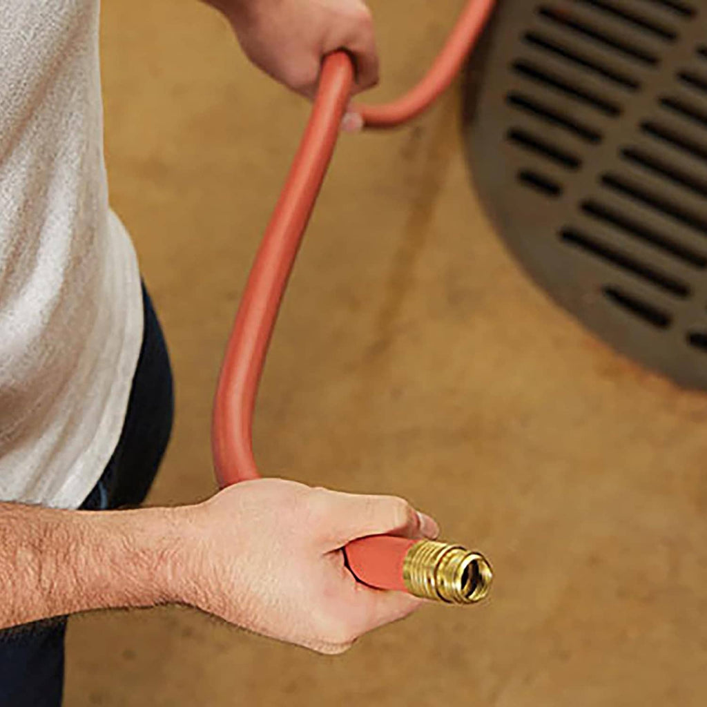 Hand holding red 3/4 in hose end with brass connector, near a spigot.