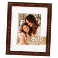 Brown beaded wood picture frame with white mat, displaying a 5x7 photo in 8x10