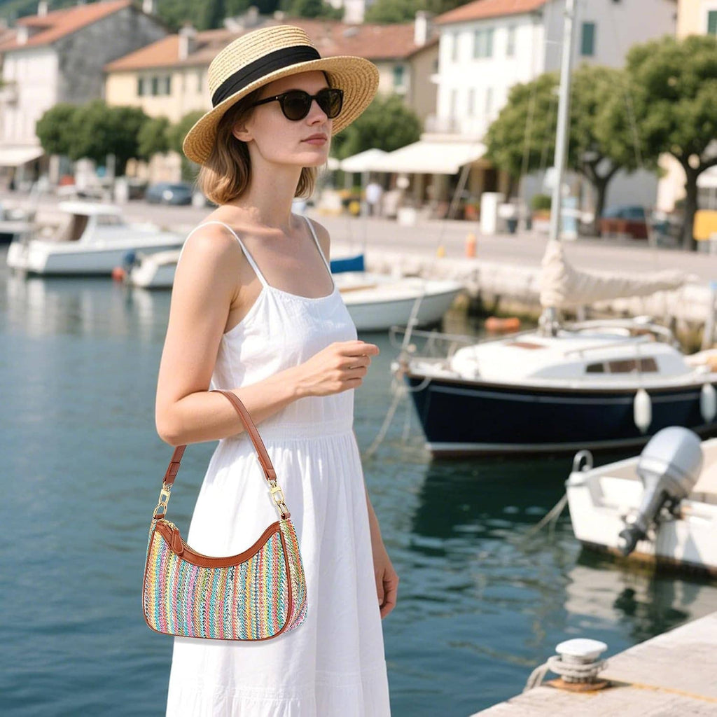 Multicolor woven hobo bag with brown strap trim and gold-tone rings, worn on shoulder.