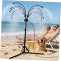 Outdoor standing misting system on tripod with 8 curved nozzle hoses over yard sand