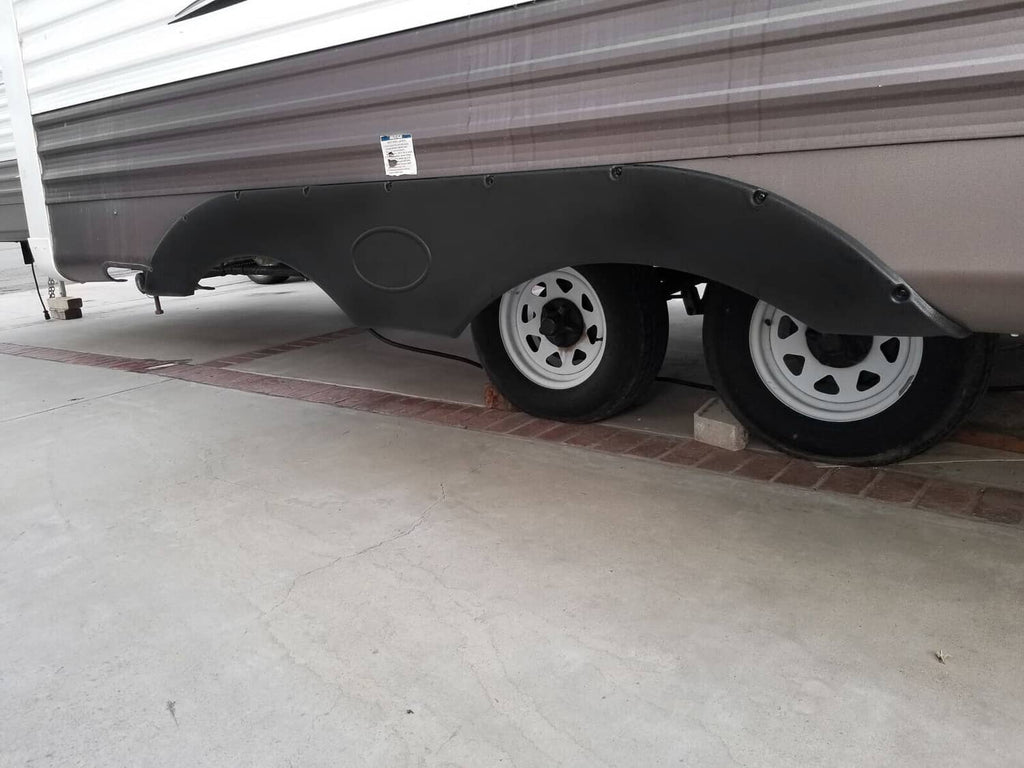 Black curved trailer fender skirt set with open wheel arches, side view.