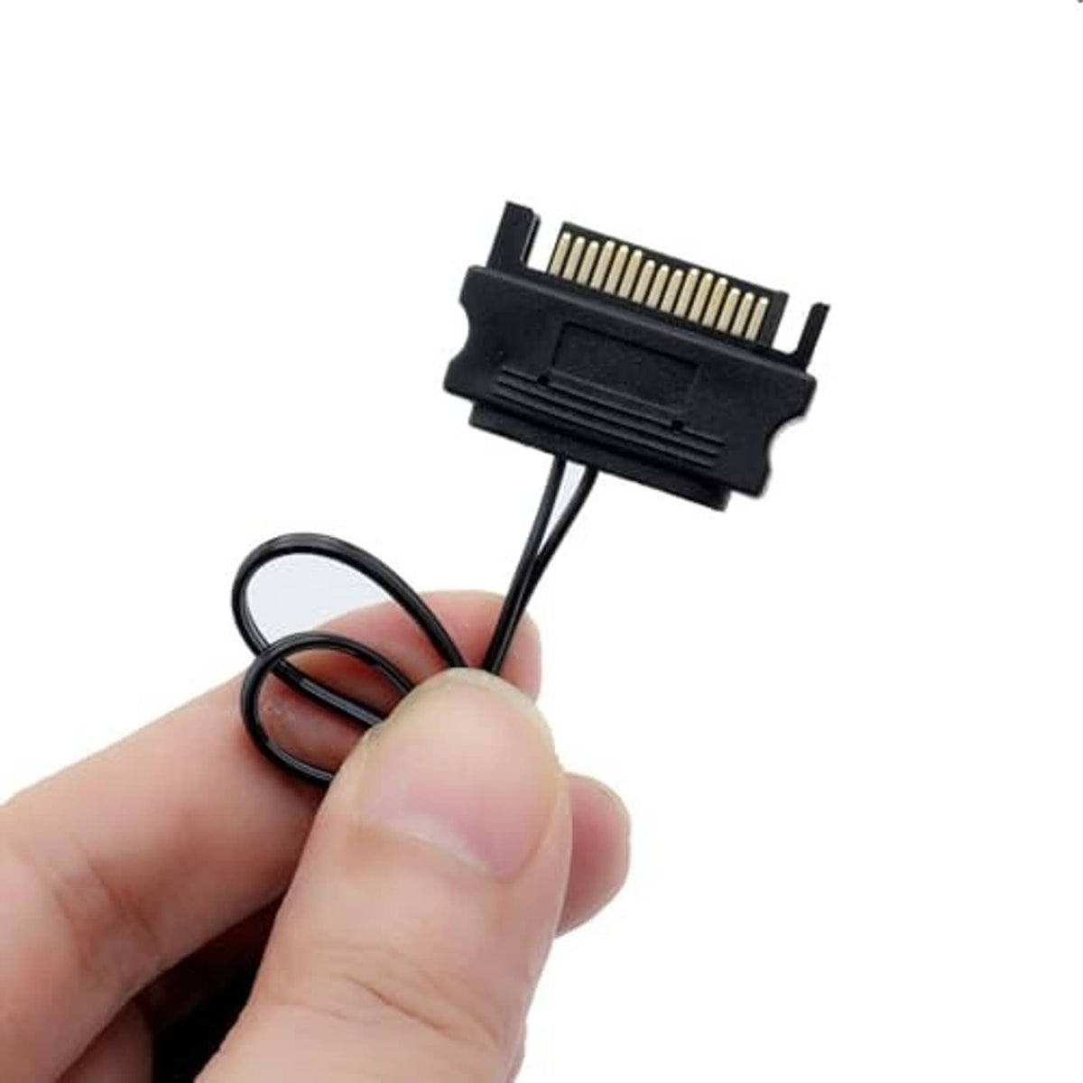Black connector with gold pins and wire leads, held in a hand