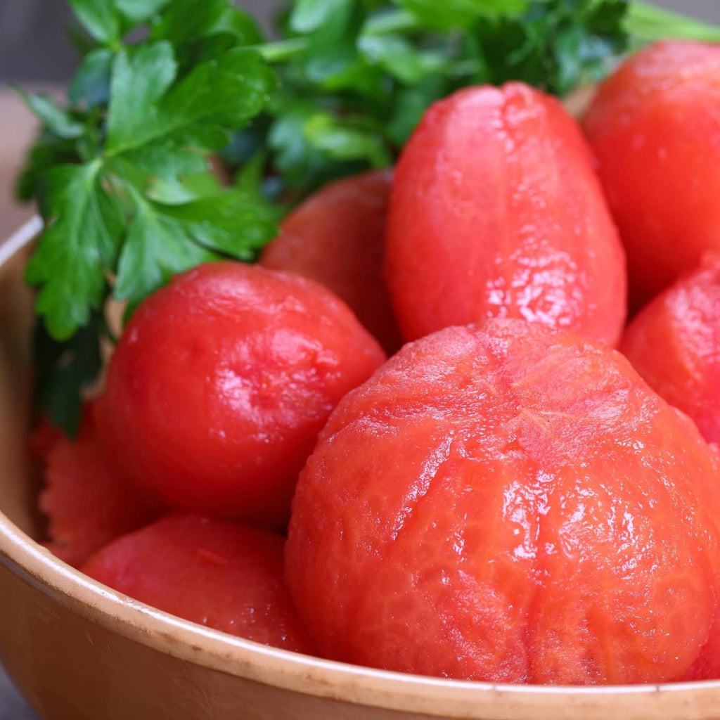 Peeled whole tomatoes in bowl with chopped parsley