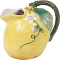 Ceramic lemon pitcher with yellow textured body, green handle, leaf accents, and white flower