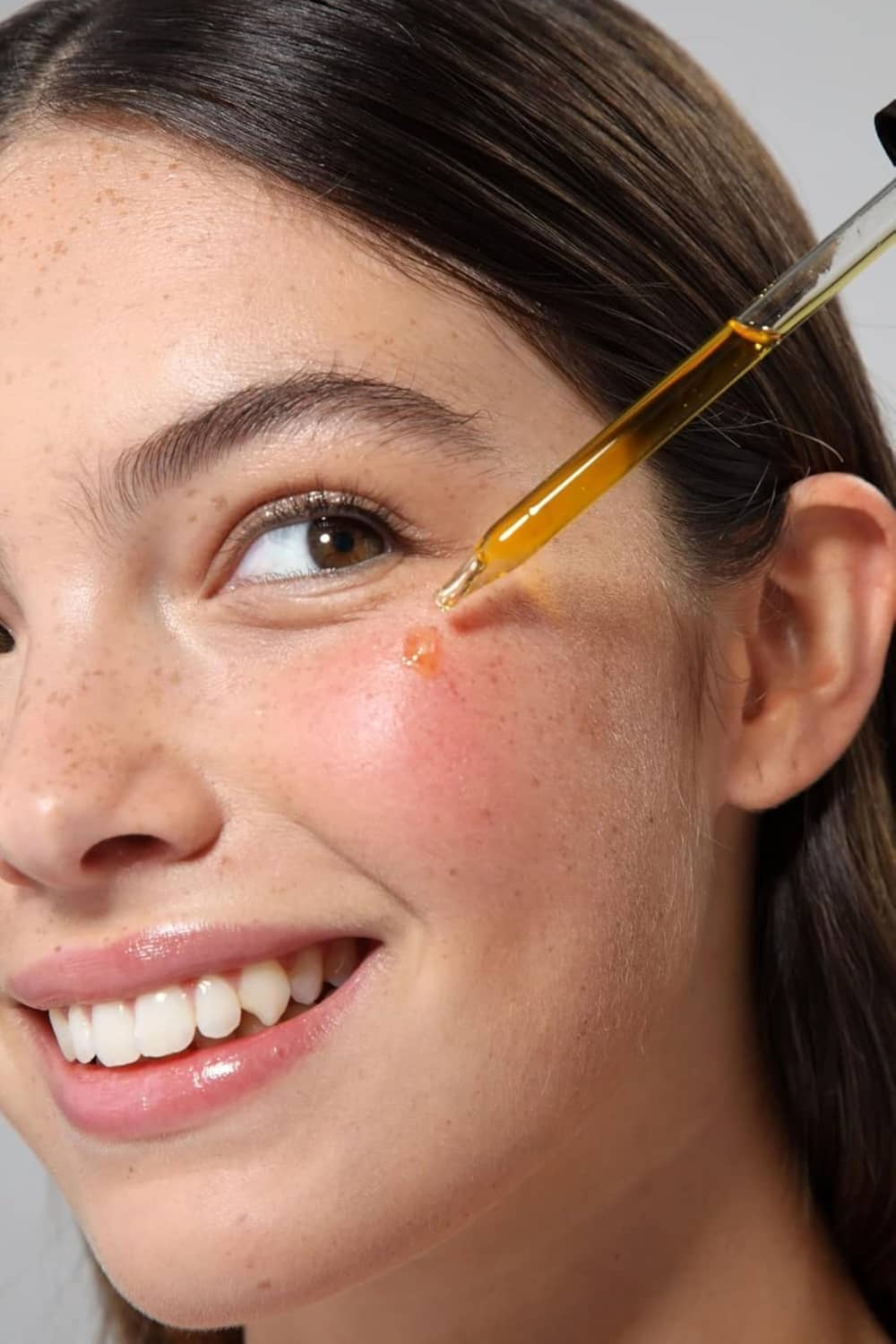 Facial skin with small droplet of Vitamin E oil from applicator