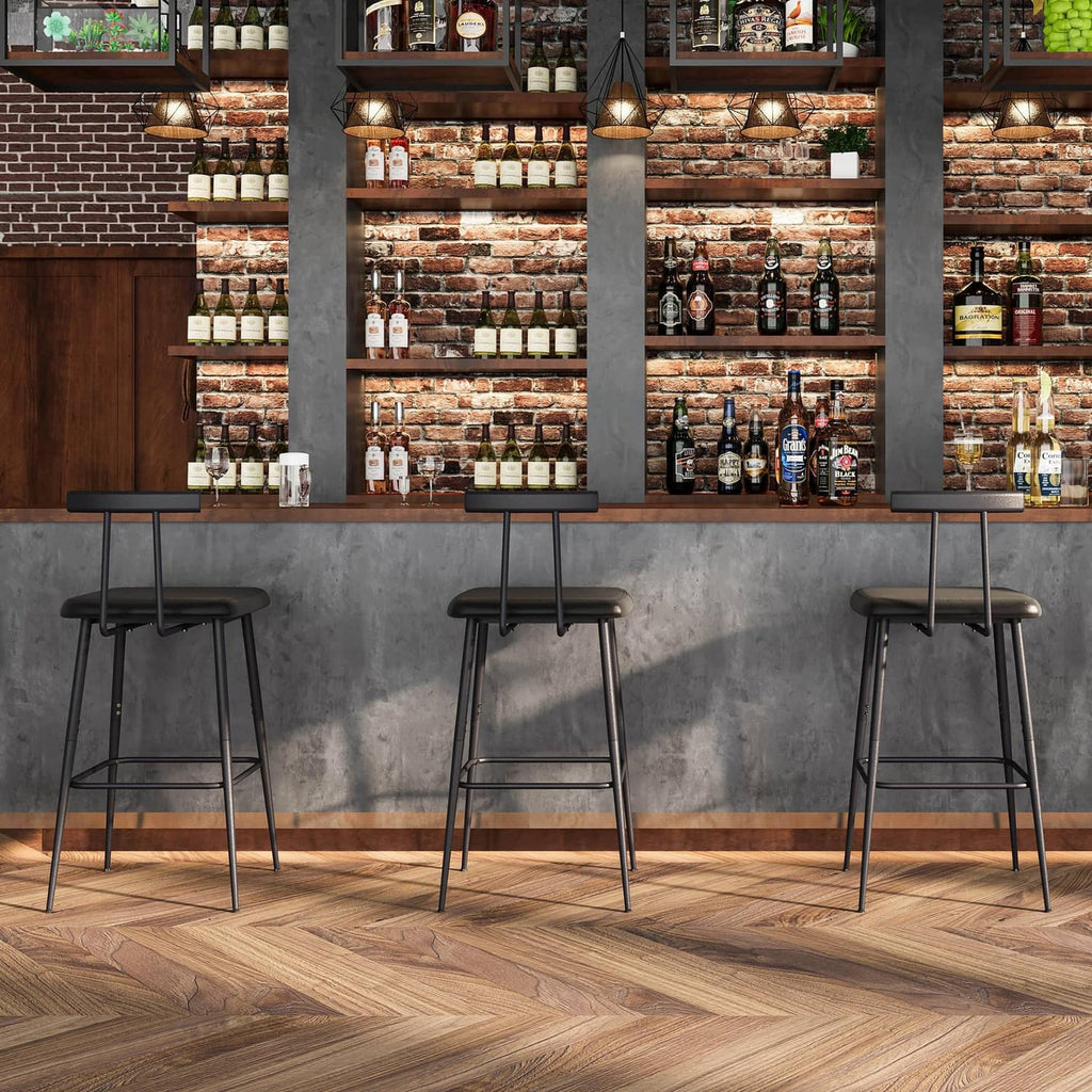 Three black bar stools with padded round seats and metal footrests