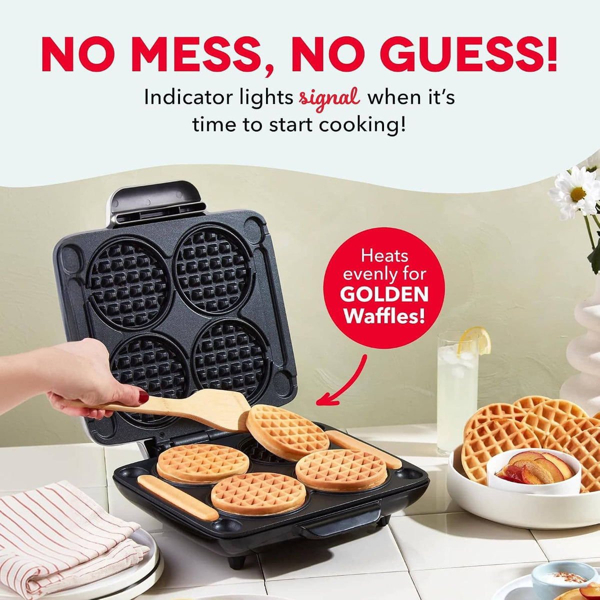 Graphite mini waffle maker open with four golden waffles and a hand pressing the lid
