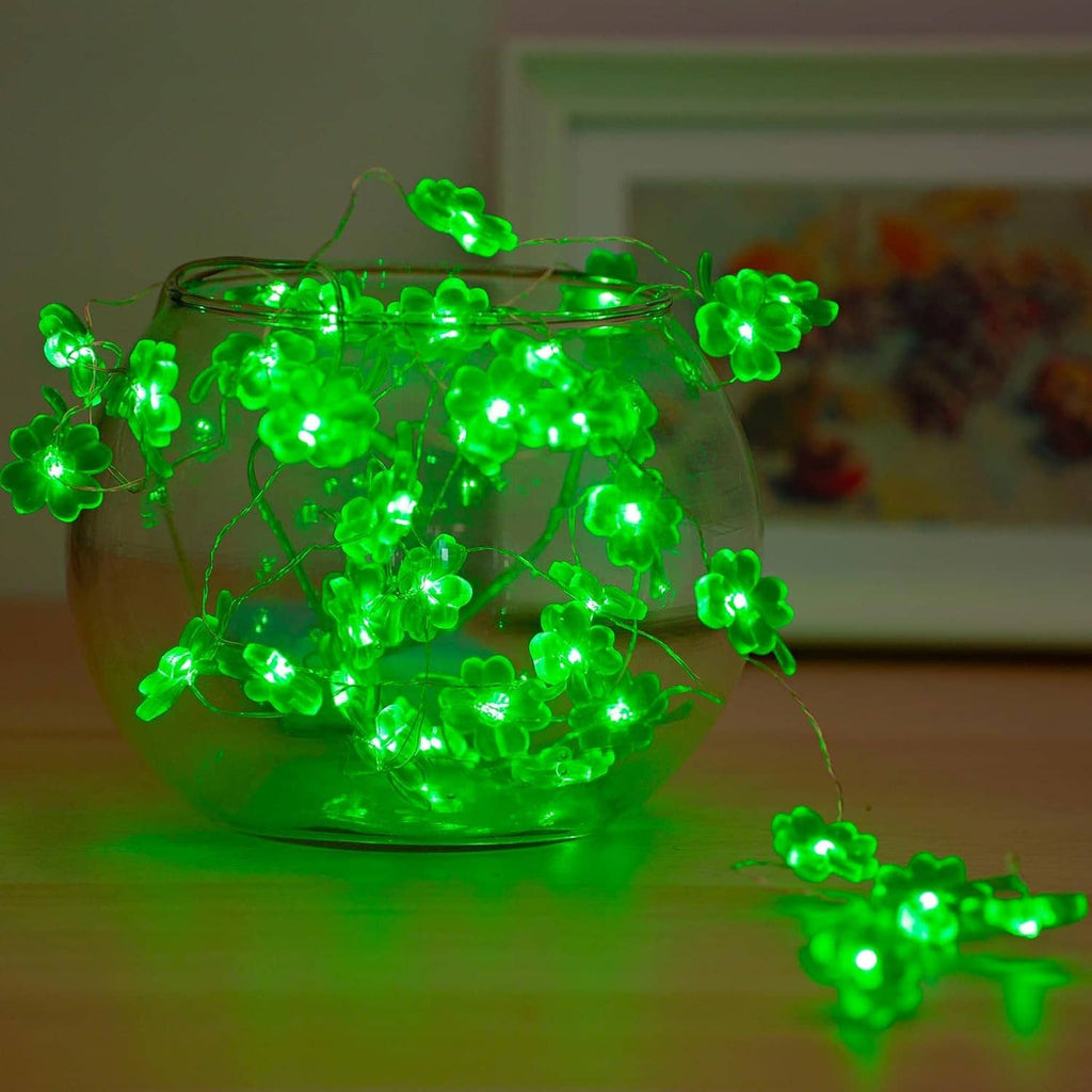 Green shamrock string lights glowing inside a clear bowl with wire clover LEDs