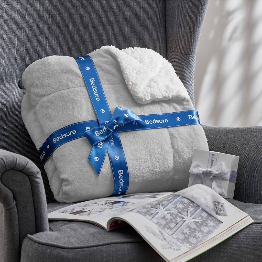 Light grey Bedsure sherpa fleece throw blanket tied with blue bow on a sofa