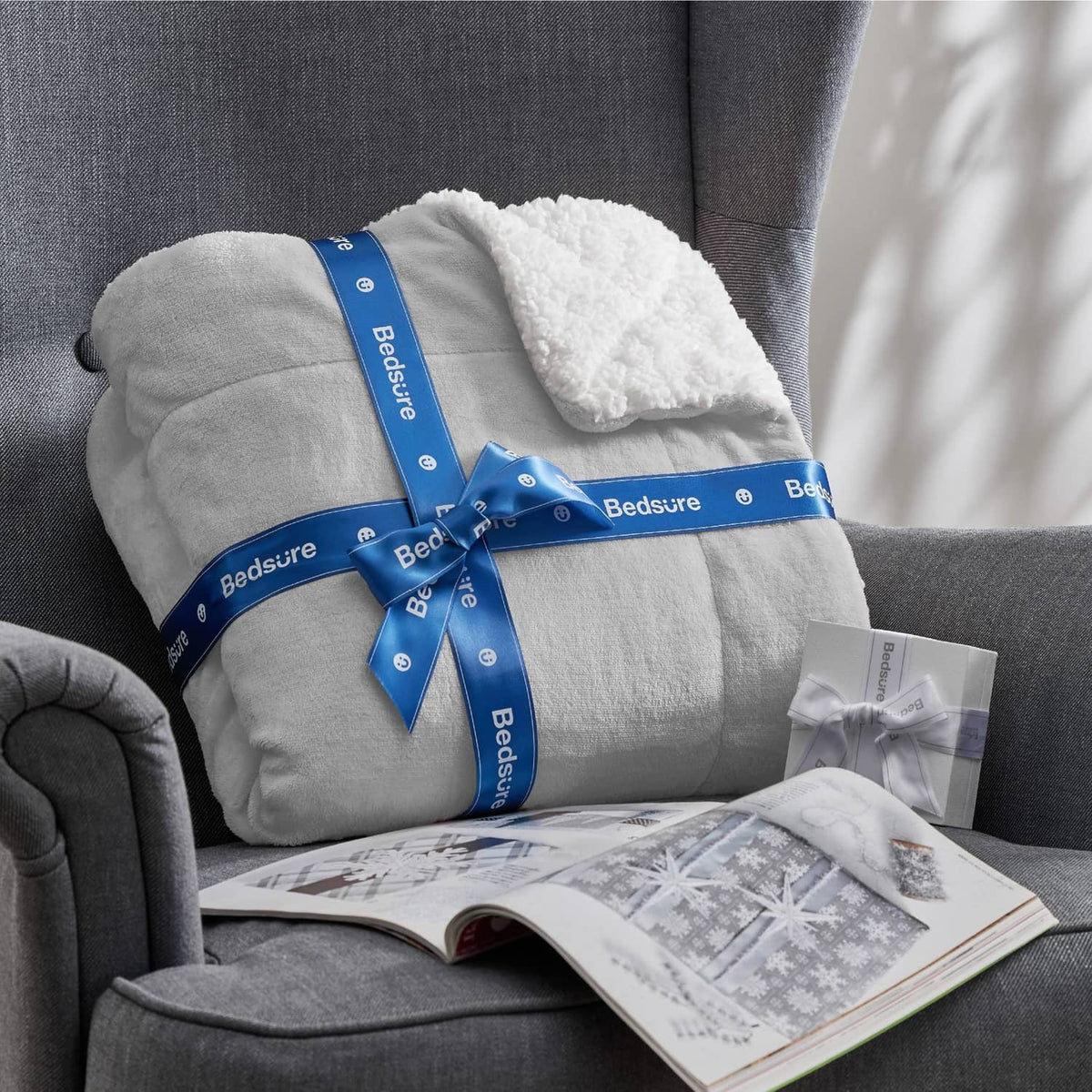 Light grey Bedsure sherpa fleece throw blanket tied with blue bow on a sofa