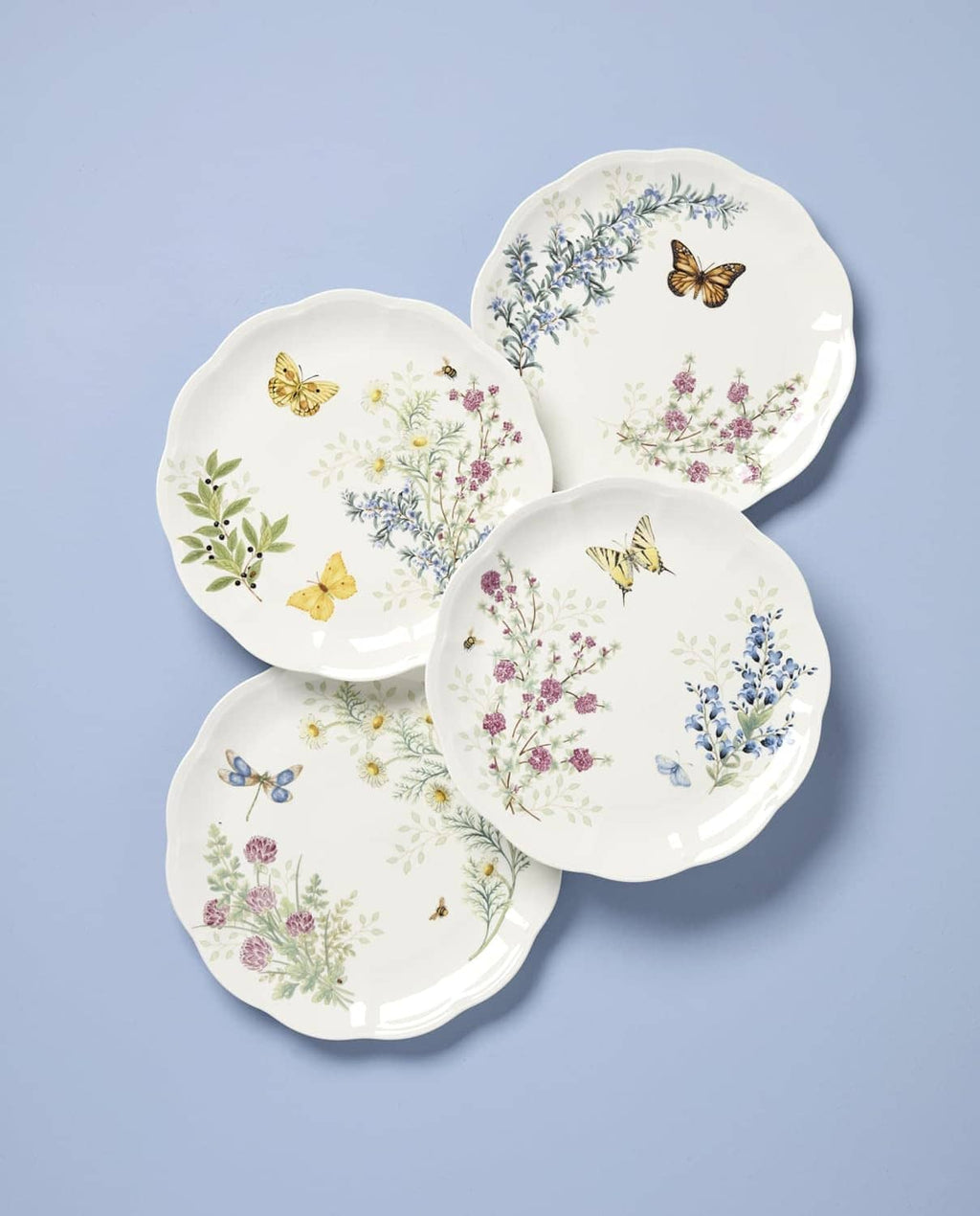Set of 4 white dinner plates with butterfly and blue/pink wildflower herb meadow designs.
