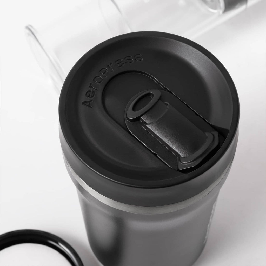 Close-up of AeroPress black filter cap and brew mechanism on clear cylinder.