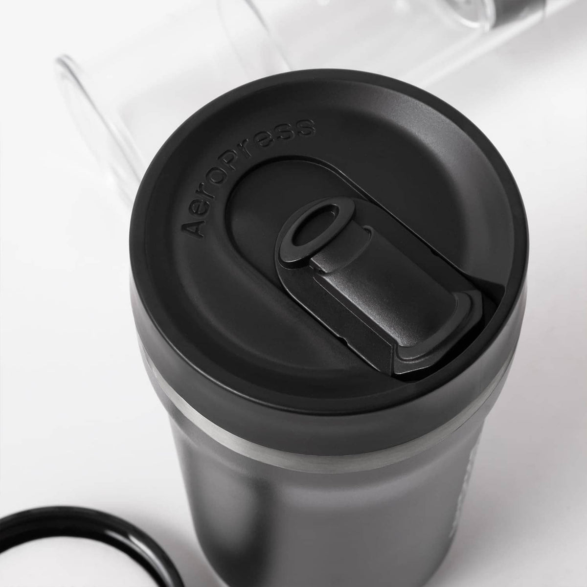 Close-up of AeroPress black filter cap and brew mechanism on clear cylinder.