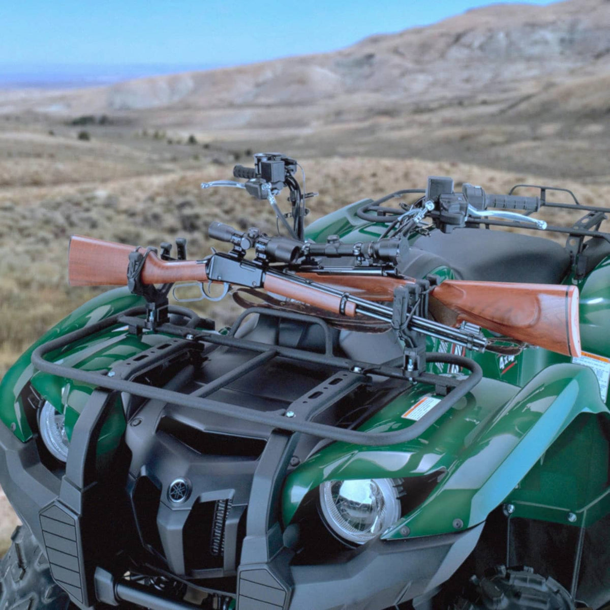 ATV with green body featuring a mounted black double gun and bow rack at front.