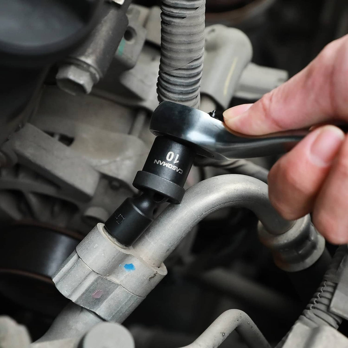 1/4 in drive socket on engine hardware, hand gripping the extension