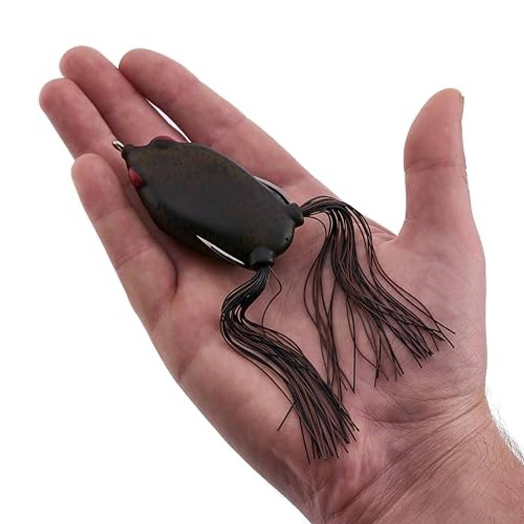 Frog fishing lure held in hand: dark camo body, red eye, long black-brown skirt