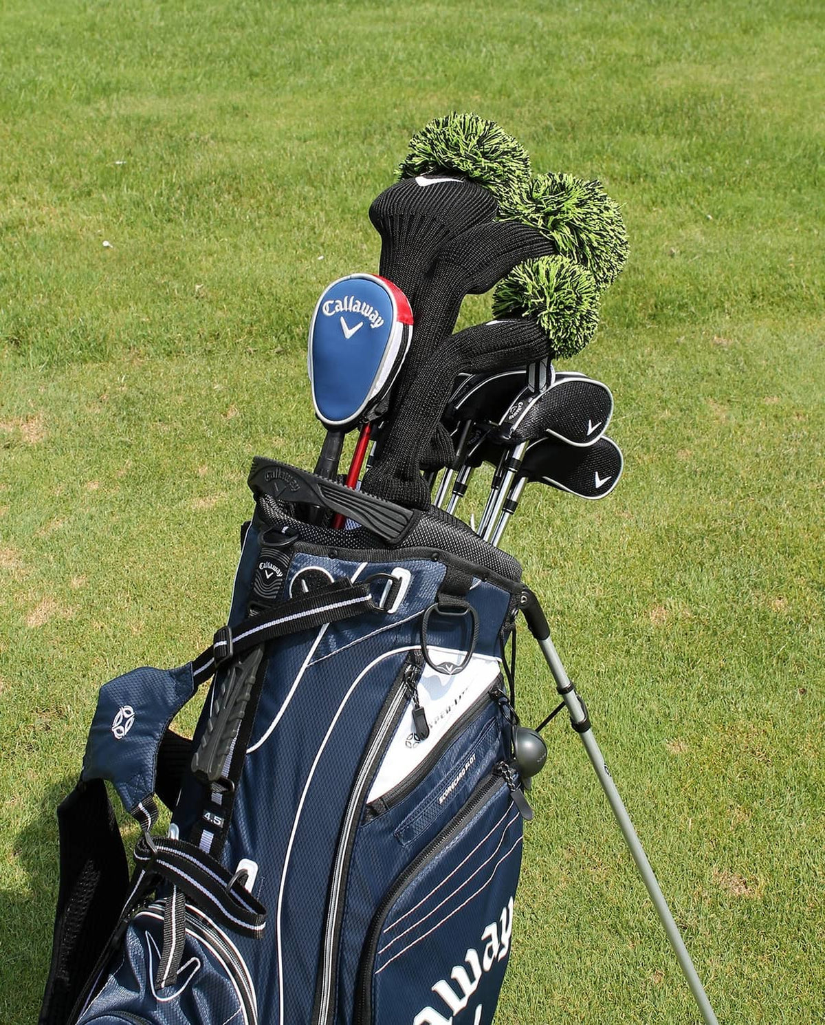Golf ball retriever pole with blue Callaway head, next to golf clubs and bag