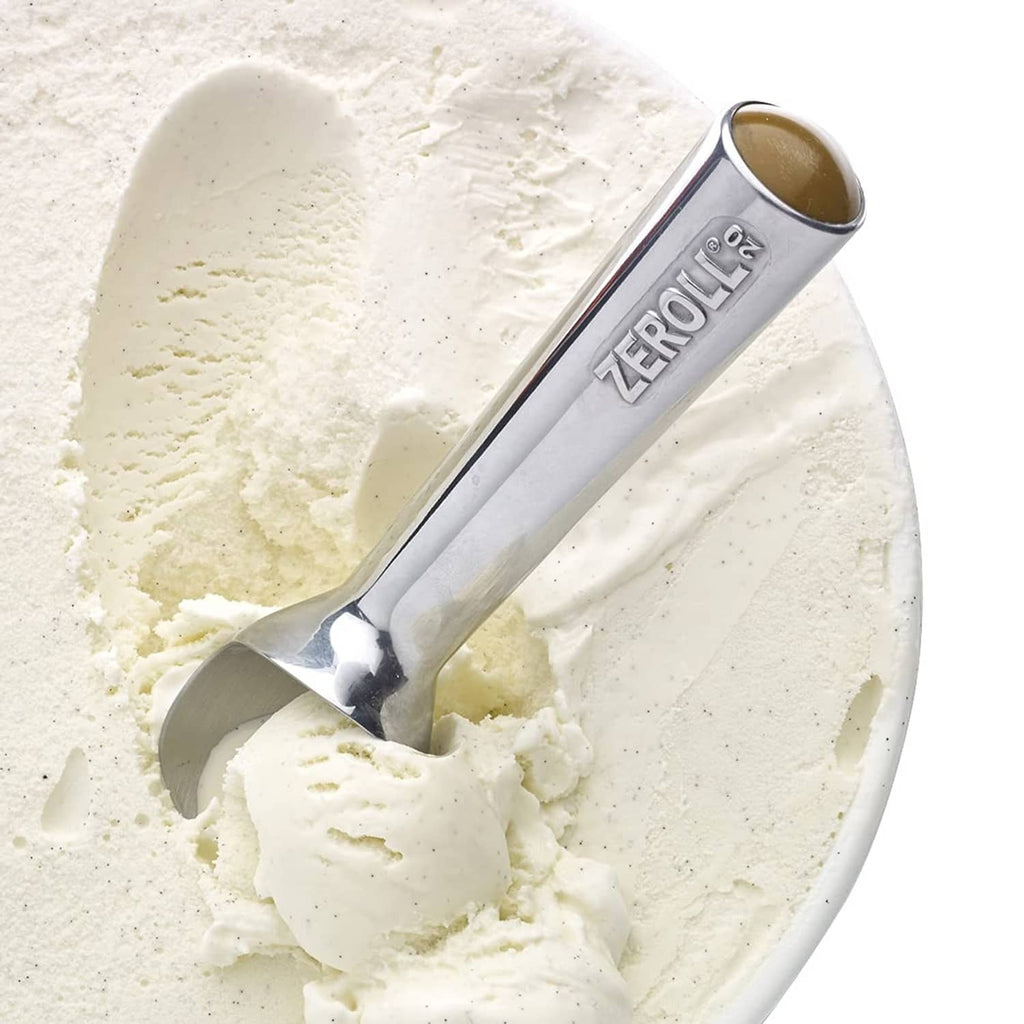 Zeroll ice cream scoop embedded in pale ice cream, silver metal bowl and handle.