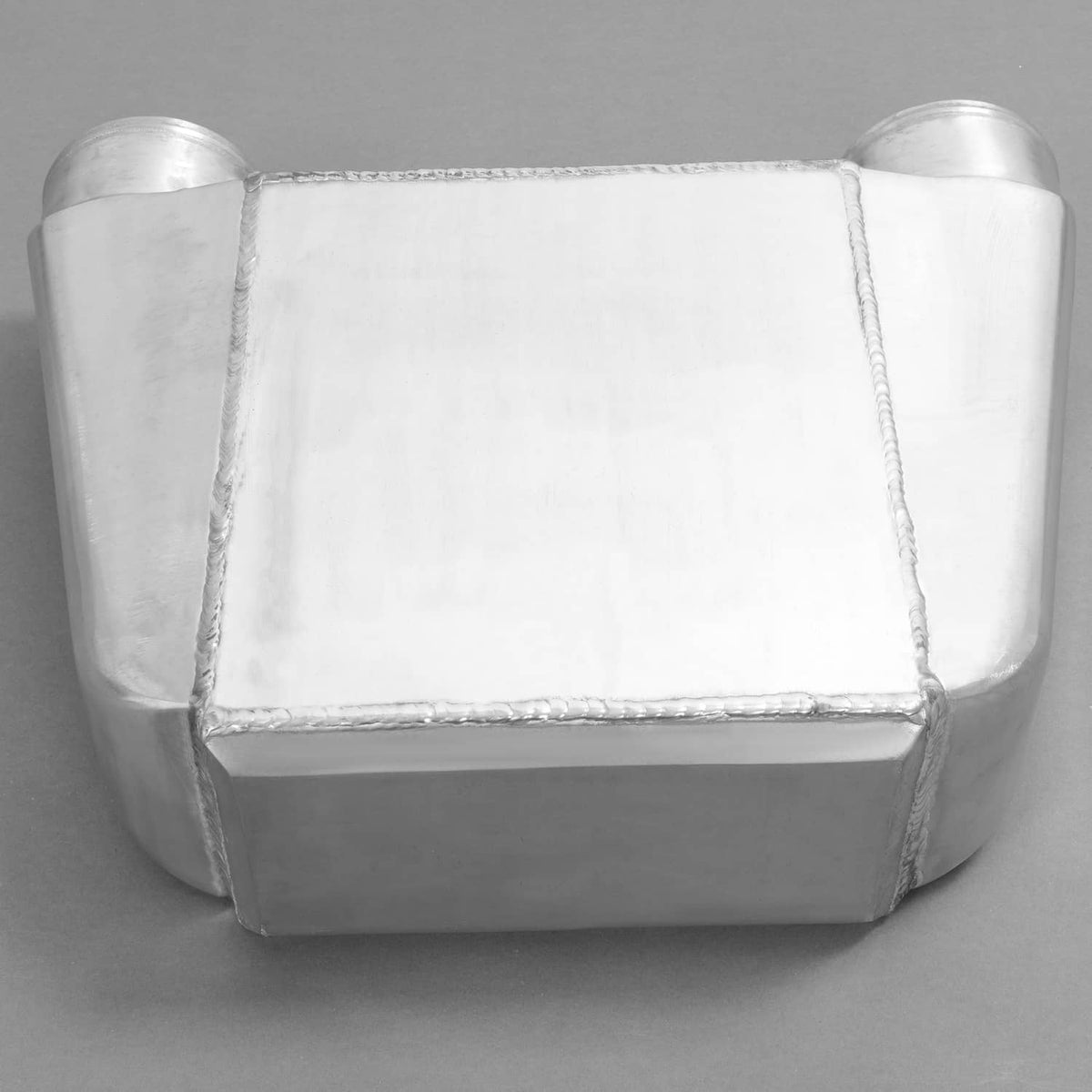 Aluminum water intercooler with rounded end tanks, rectangular core, welded seams.