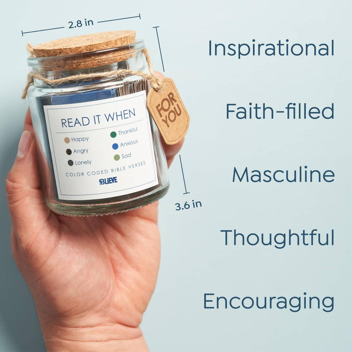 Small glass Bible verse jar with blue label and kraft 'for you' tag, held in hand.