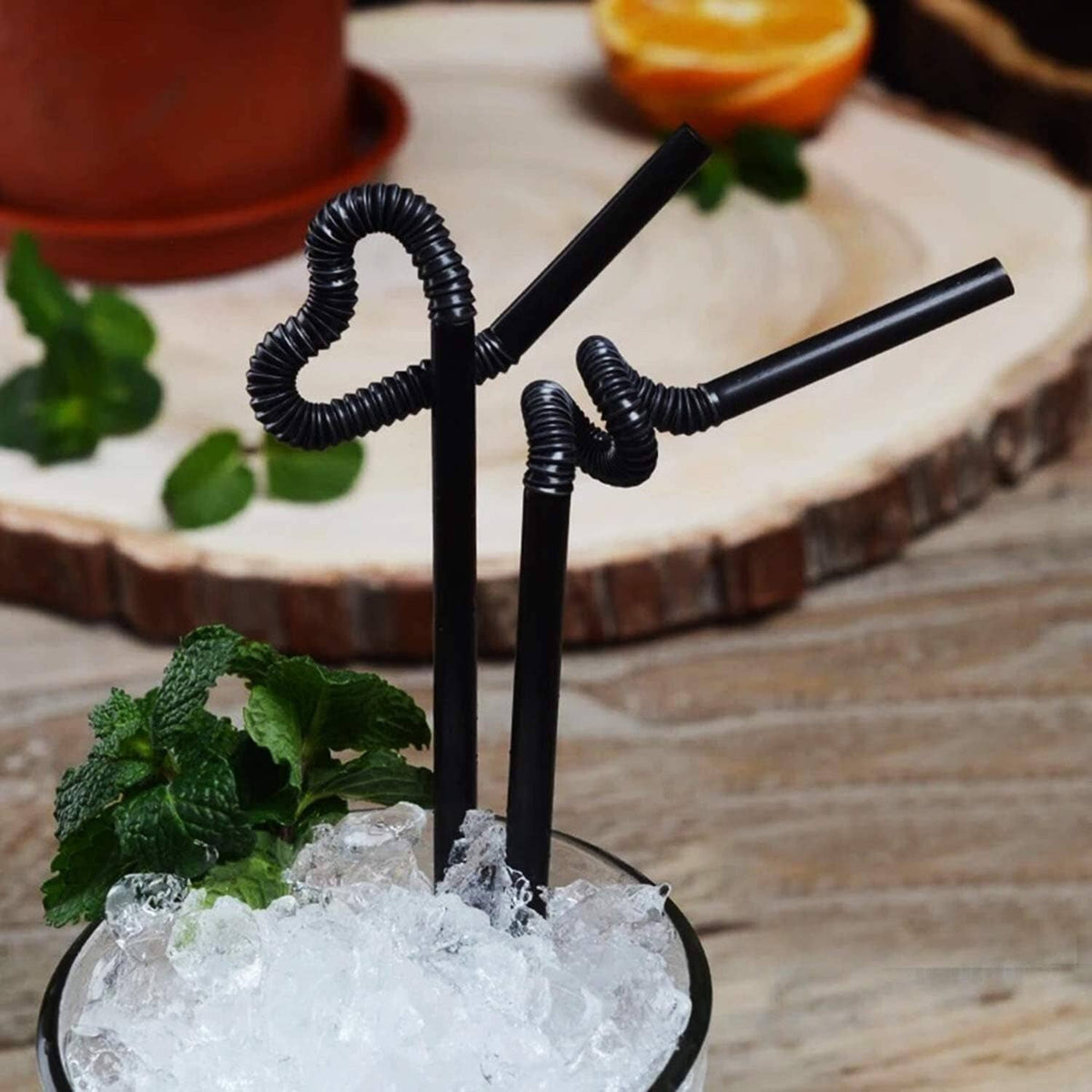Extra-long black curly drinking straws in a glass of ice water