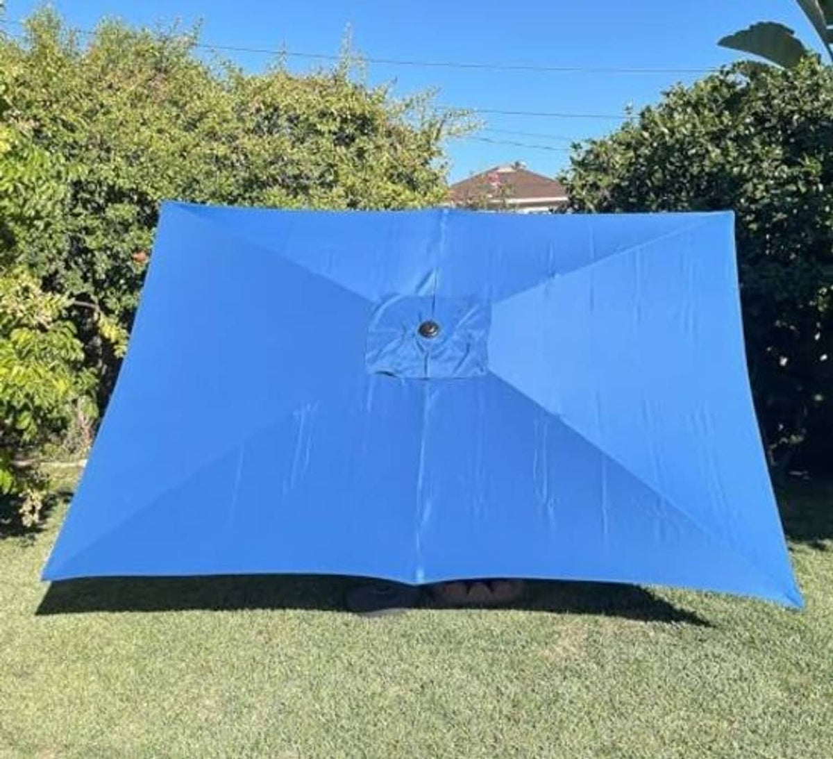 Blue rectangular replacement umbrella canopy opened in yard, with center button and seams.