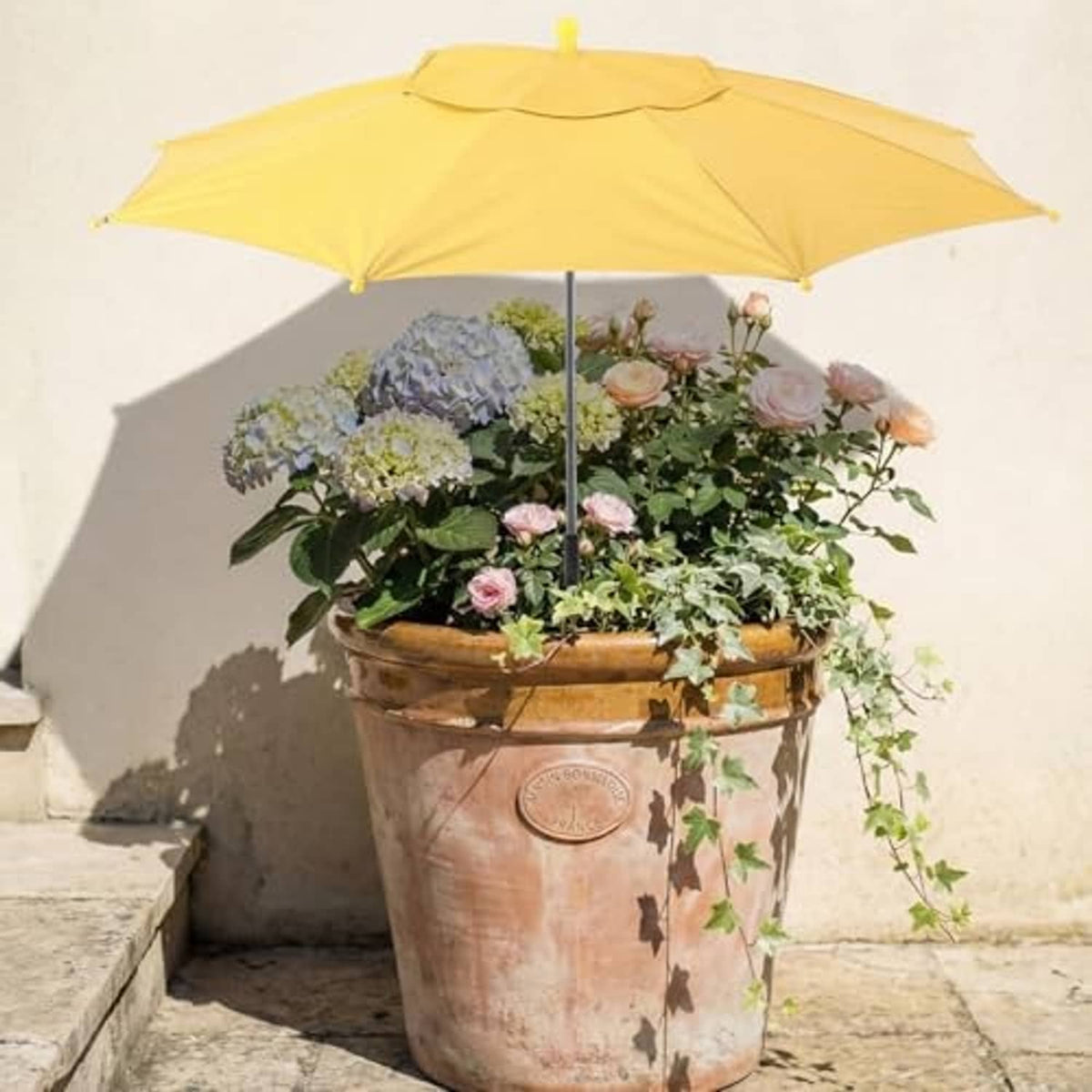 Yellow plant shade umbrella above mixed flowers in a large round pot