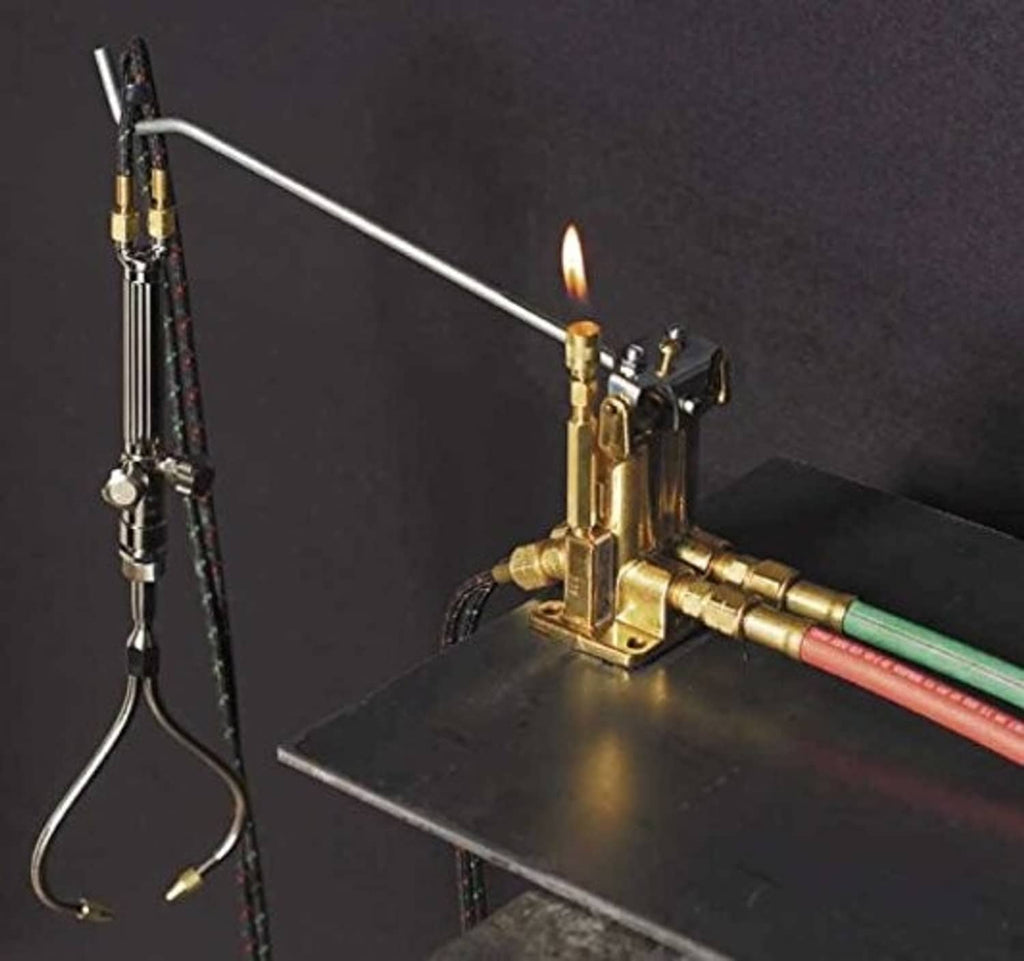 Brass gas acetylene/oxygen torch valve manifold with visible flame at the tip