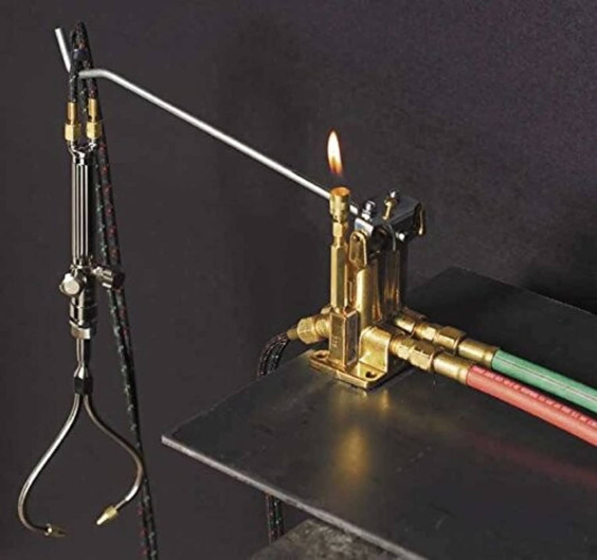 Brass gas acetylene/oxygen torch valve manifold with visible flame at the tip
