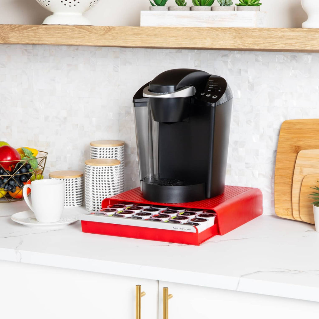 Red coffee pod drawer on countertop with black single-serve brewer and pod tray