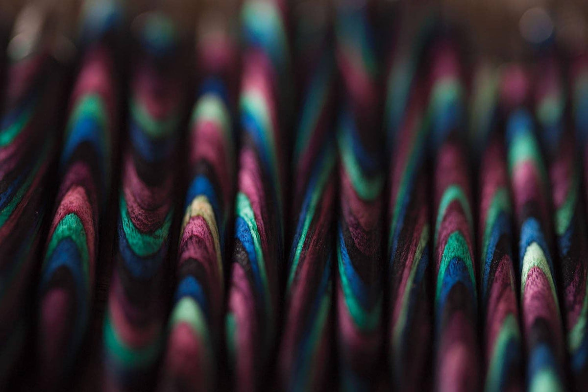 Close-up of colorful mosaic wood knitting needle shafts with teal and pink tones
