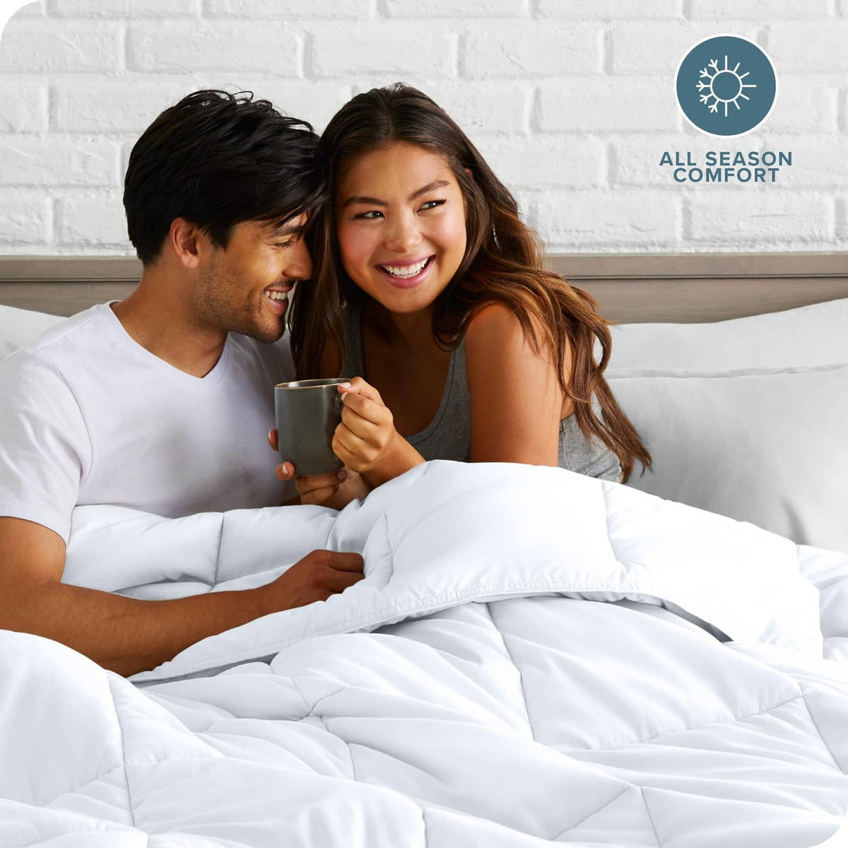 White down-alternative comforter on bed as people cuddle under the bedding