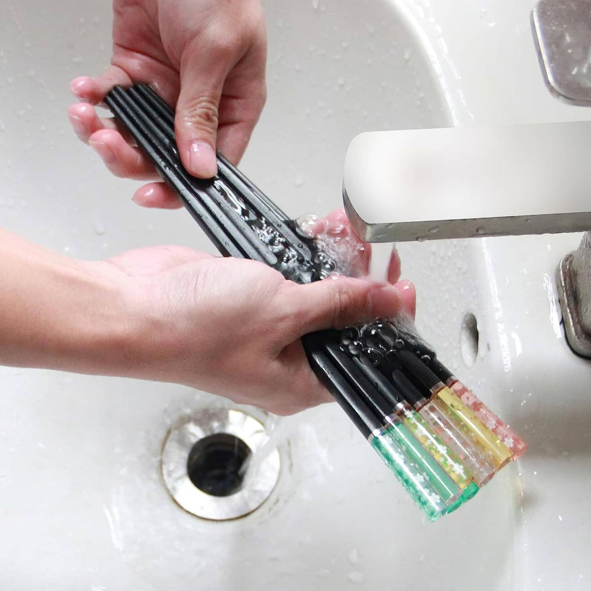 Reusable chopsticks being washed under running water at a sink