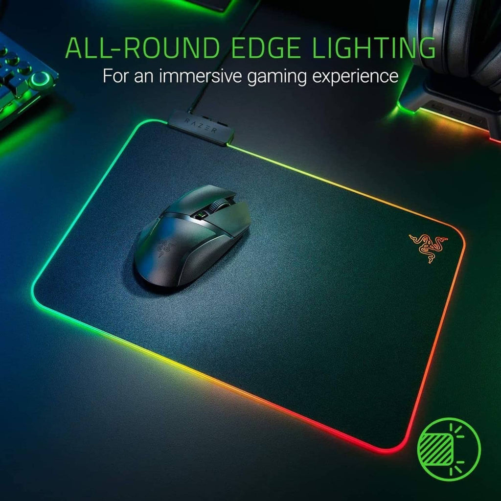RGB edge-lit gaming mouse pad with Razer logo and mouse resting on hard surface
