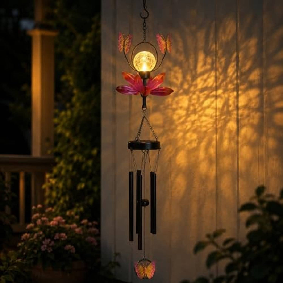 Solar outdoor wind chime glowing at night with butterfly flower spinner and hanging tubes