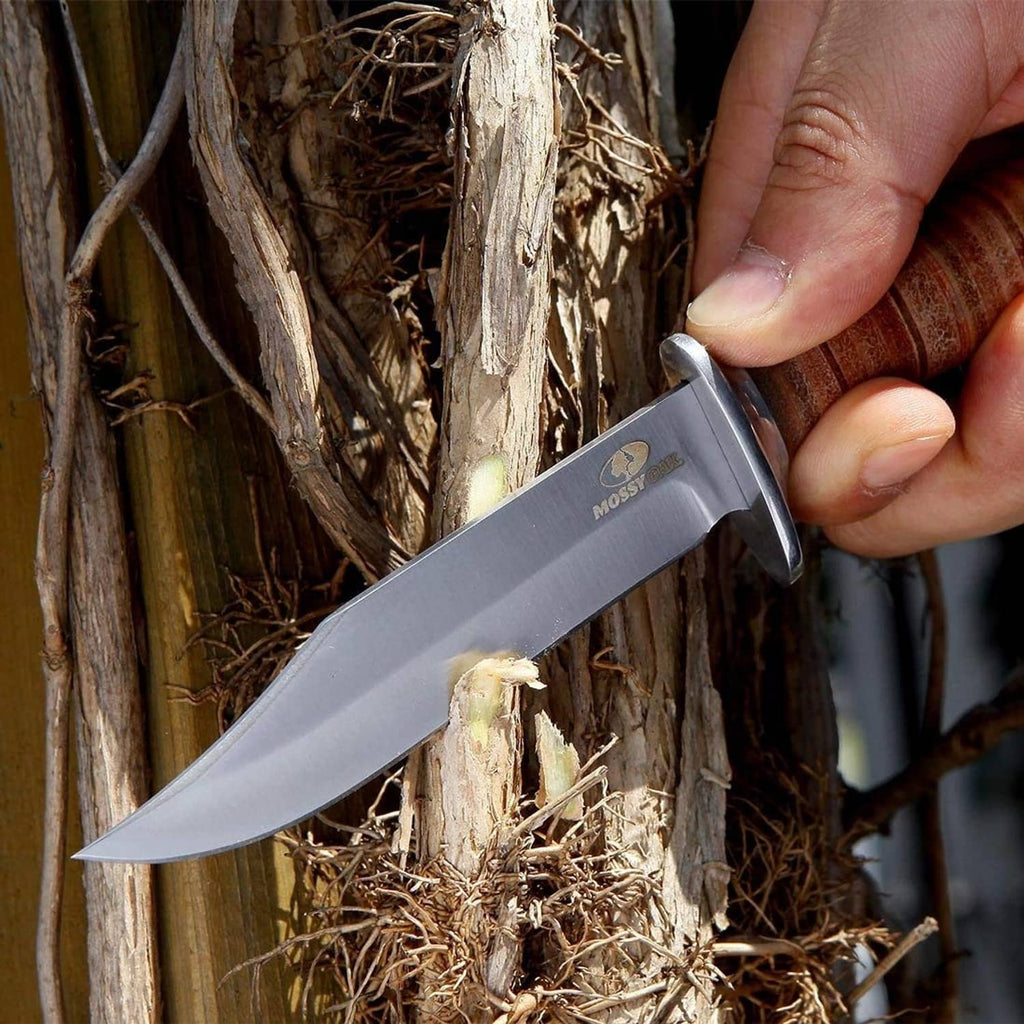 Bowie knife in hand with wood handle and stainless blade near cut wood